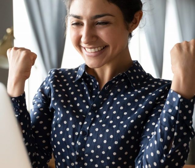 Overjoyed,Indian,Ethnicity,Girl,Sit,At,Desk,Looks,At,Laptop